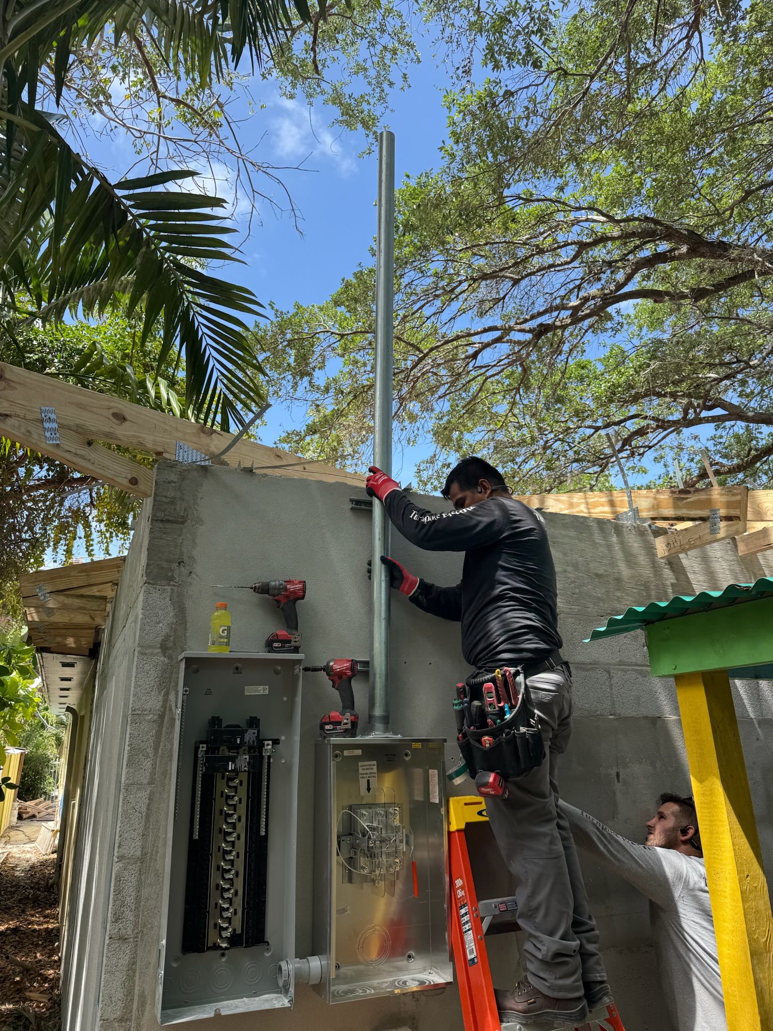 Electrician installing a service mast and conduit above new panels